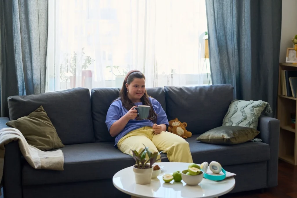Girl with down syndrome sitting on couch enjoying a cup of tea