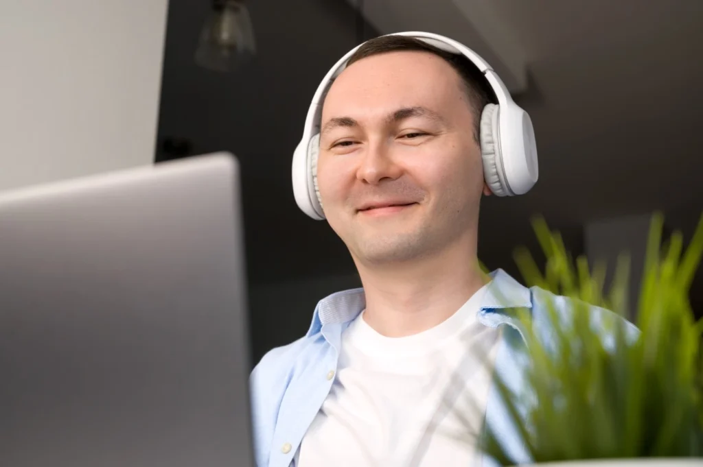 Disabled man wearing headphones and looking at laptop
